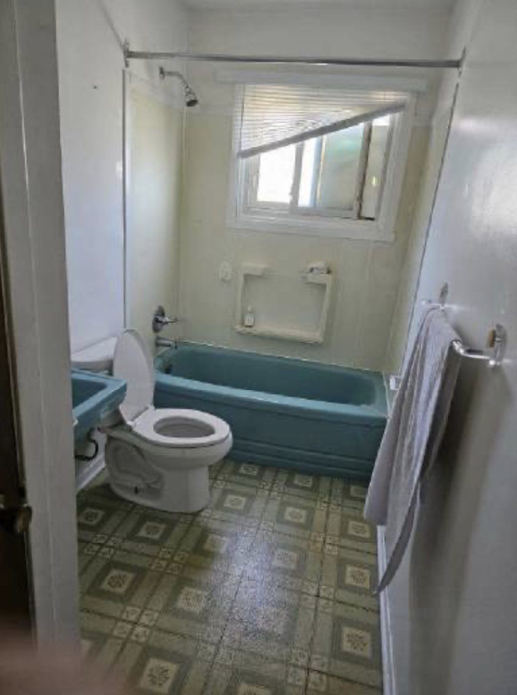 Bathroom before: old turquoise tub, fixtures and vinyl floor