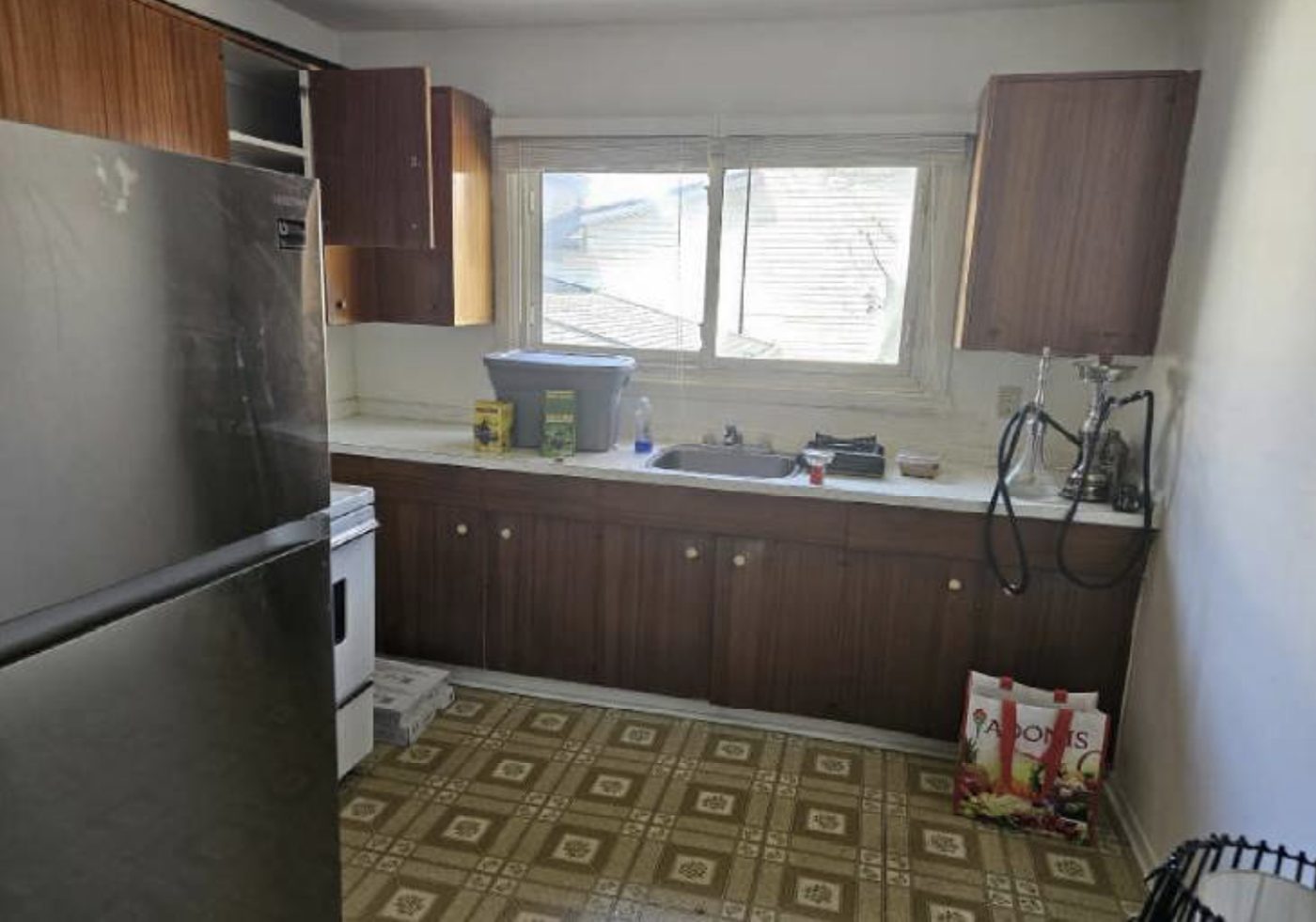 Kitchen before: dark wood cabinets and patterned vinyl floor