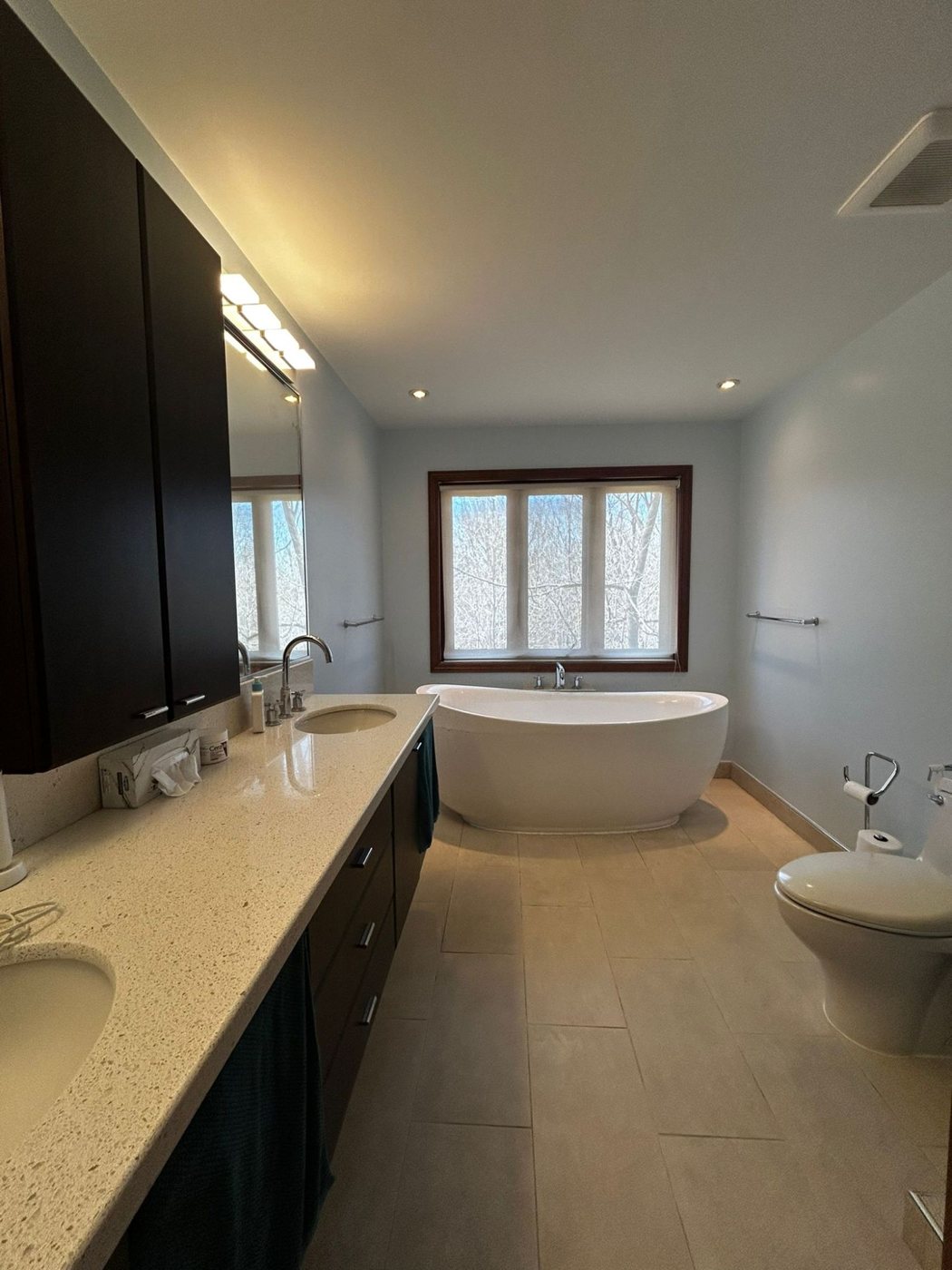 Ensuite bathroom with double vanity, freestanding soaking tub and large-format floor tile